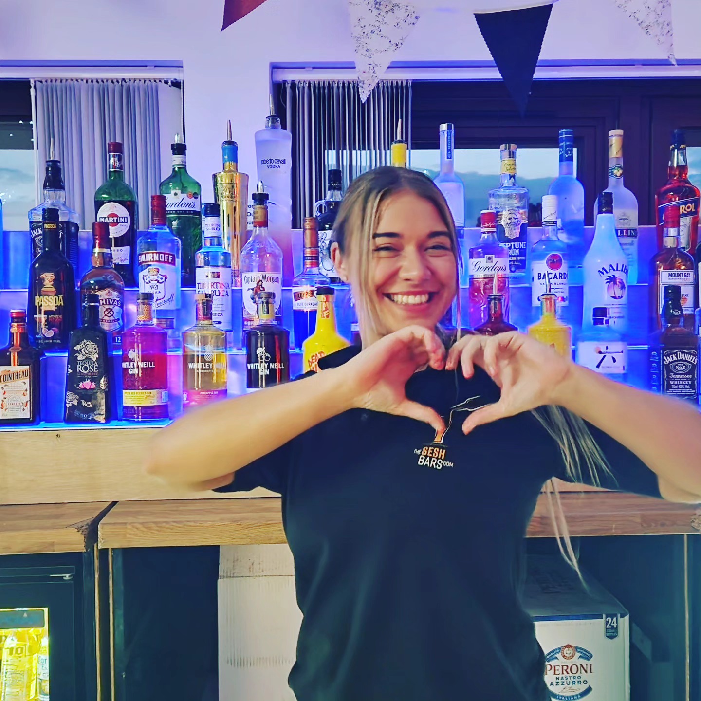 Bartender making a heart shape with hands behind the bar at a London birthday party